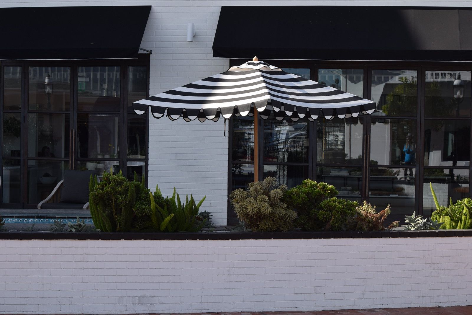White-brick storefronts and a striped umbrella at Lido Marina Village